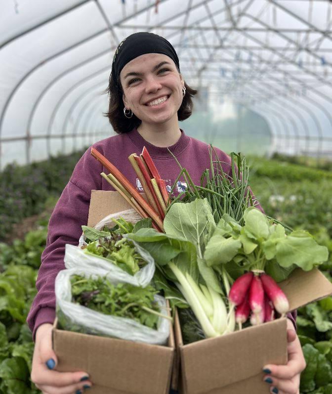 Student posing with a full CSA share.